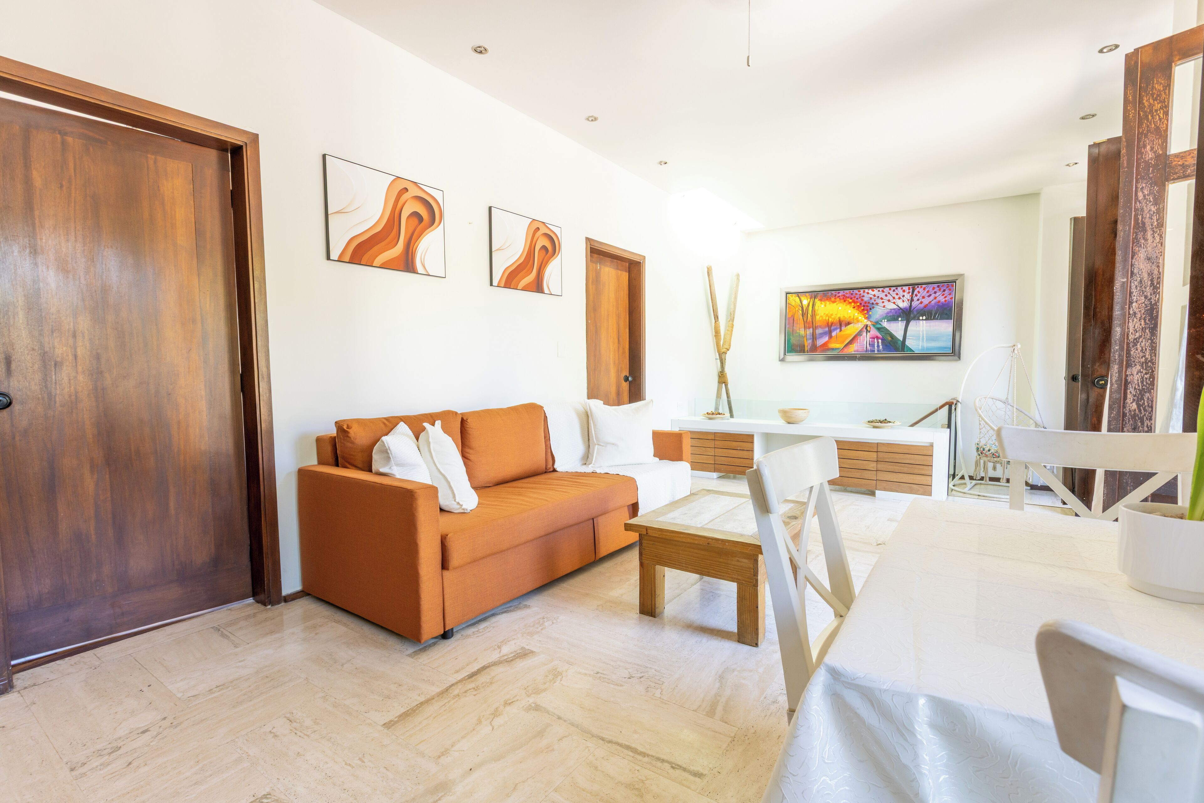 Uma sala de estar moderna com porta de madeira, sofá, mesa de centro e área de jantar com cadeiras e mesa.