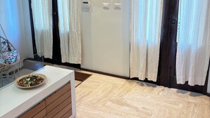 Ein modernes Zimmer mit Fischgrätparkett, einem weißen Konsolentisch und einer Glastrennwand.