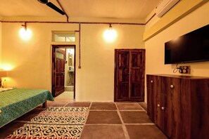 Ein Schlafzimmer mit Bett, Kleiderschrank, Fernseher und einem gemusterten Teppich.
