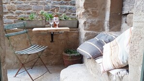 A rustic outdoor seating area with a wooden table, a metal chair, and a cushioned bench. - Cozy, spacious studio / loft in charming Les Vans. Monts d'Ardèche natural park. (Les Vans)