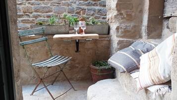Un espace extérieur aménagé dans un style rustique, avec une table en bois, une chaise en métal et un banc rembourré.