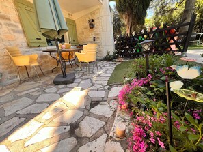 Un patio empedrado con mobiliario exterior, un muro de piedra y una cerca de madera.