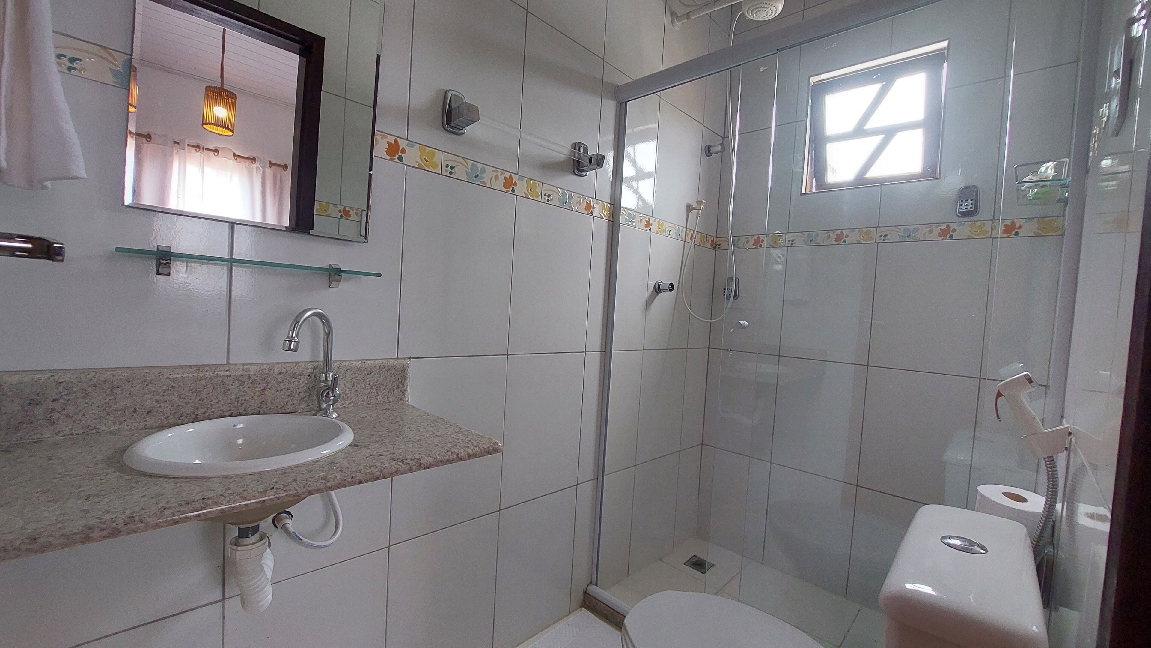Een badkamer met een wastafel, spiegel, douche en toilet.