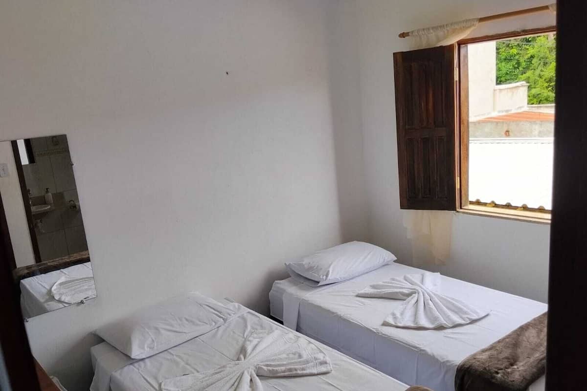 A room with two beds, a window with a view, and a mirror.
