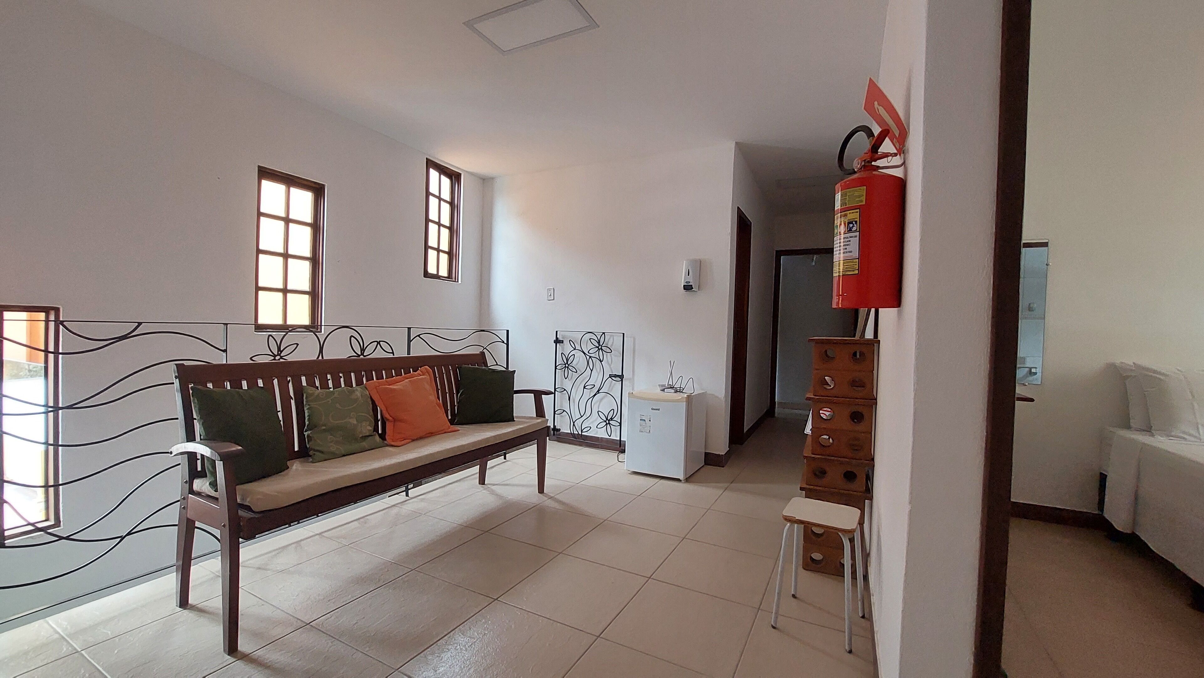 A room with a wooden bench, a refrigerator, a small table, and a fire extinguisher.