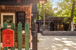 A brick building with a mailbox, wooden fence, and outdoor seating area. - Balchill House With Sauna And Jacuzzi (Balatonszepezd)