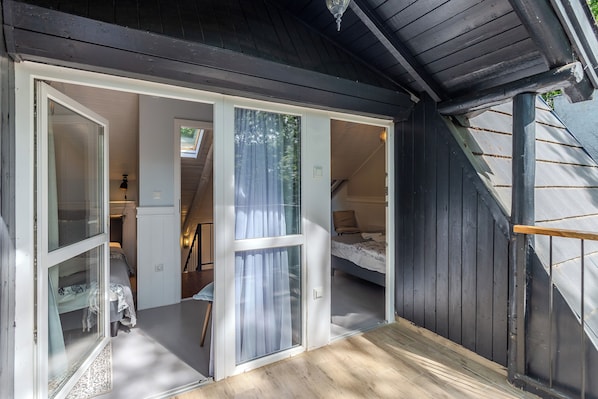 Un dormitorio con cama, ventana con cortinas y piso de madera.