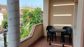 A balcony with a tiled floor, a table with chairs, and a view of greenery and buildings. - Beautiful apartment between the Alhambra and Sierra Nevada. (Cenes de la Vega)