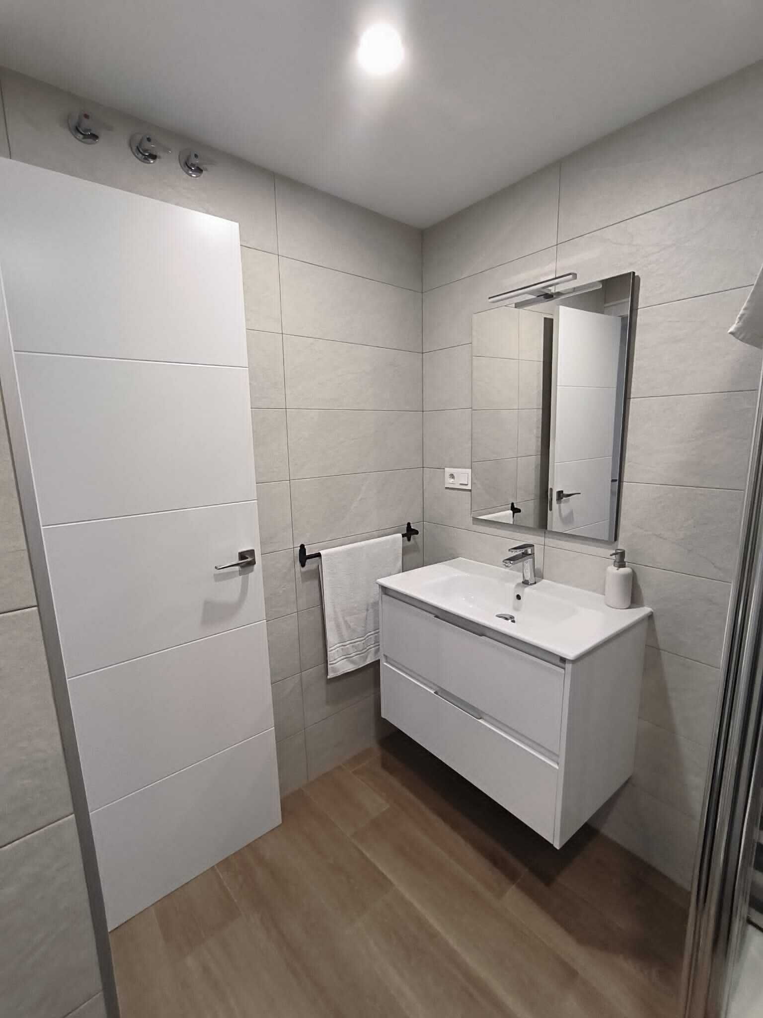 Une salle de bain moderne avec un meuble-lavabo blanc, un miroir et un porte-serviettes.