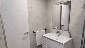 A modern bathroom with a white vanity, a mirror, and a towel rack. - Beautiful apartment between the Alhambra and Sierra Nevada. (Cenes de la Vega)