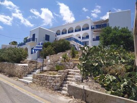Un edificio blanco con detalles azules y una escalera de piedra que lleva a la entrada.