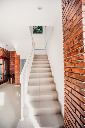 A staircase with beige steps leading to a landing with a white railing. - Pondok Yogi Guest House Canggu (Canggu)