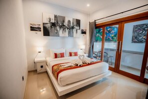 Een hotelkamer met een bed, nachtkastjes, kunst aan de muur en een schuifglazen deur naar buiten.