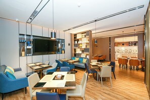 Eine moderne Hotelhalle mit Sitzgelegenheiten, einer Bar und einem an der Wand befestigten Fernseher.