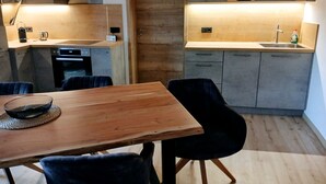 A modern kitchen with a wooden table and chairs, a built-in oven, and a sink. - Apartment 55 sqm for 2 persons with balcony and mountain view (Anger)