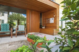Un área de estar moderna al aire libre con sillas de madera y una jardinera con flores.