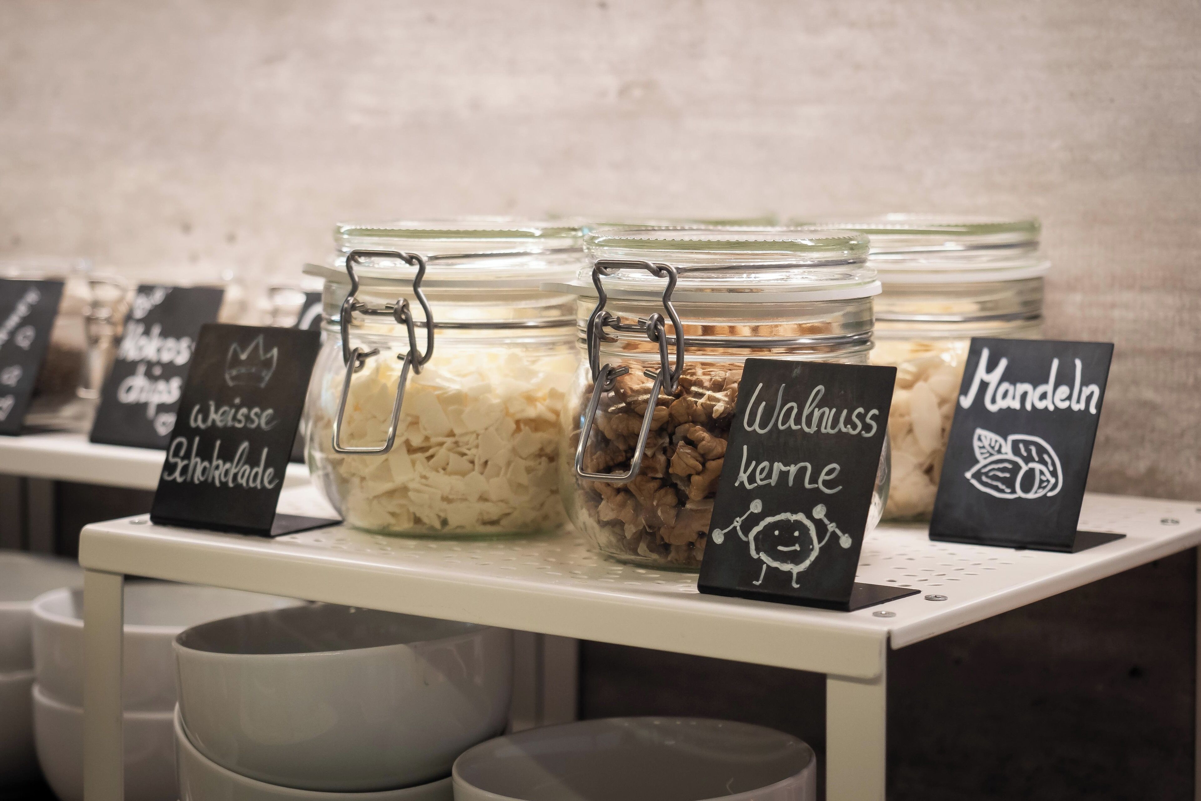 A display of food items in glass jars with labels indicating different types of chocolates and snacks.