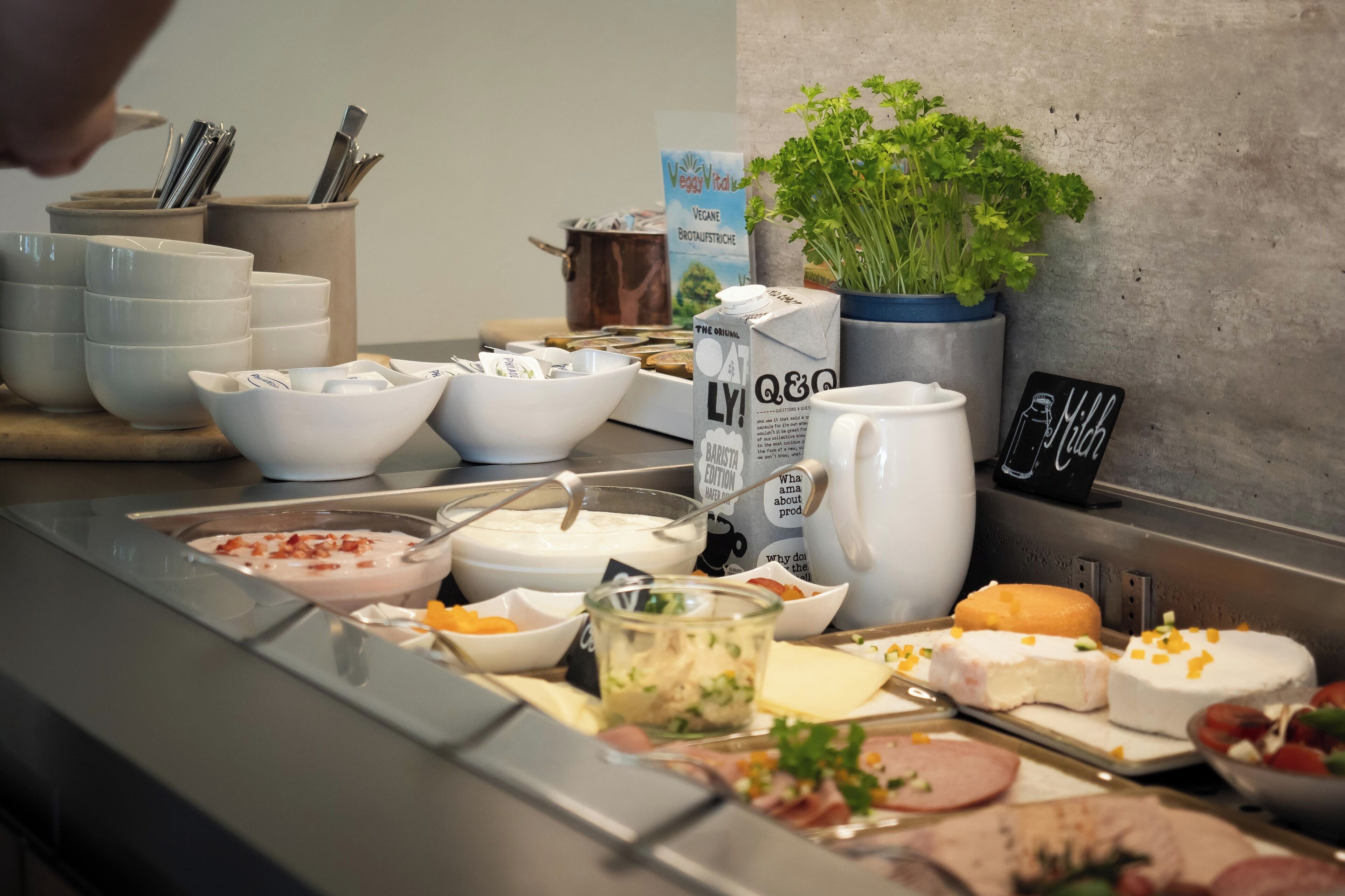 A buffet setup with various food items, including bowls of soup, cheese, and meat.