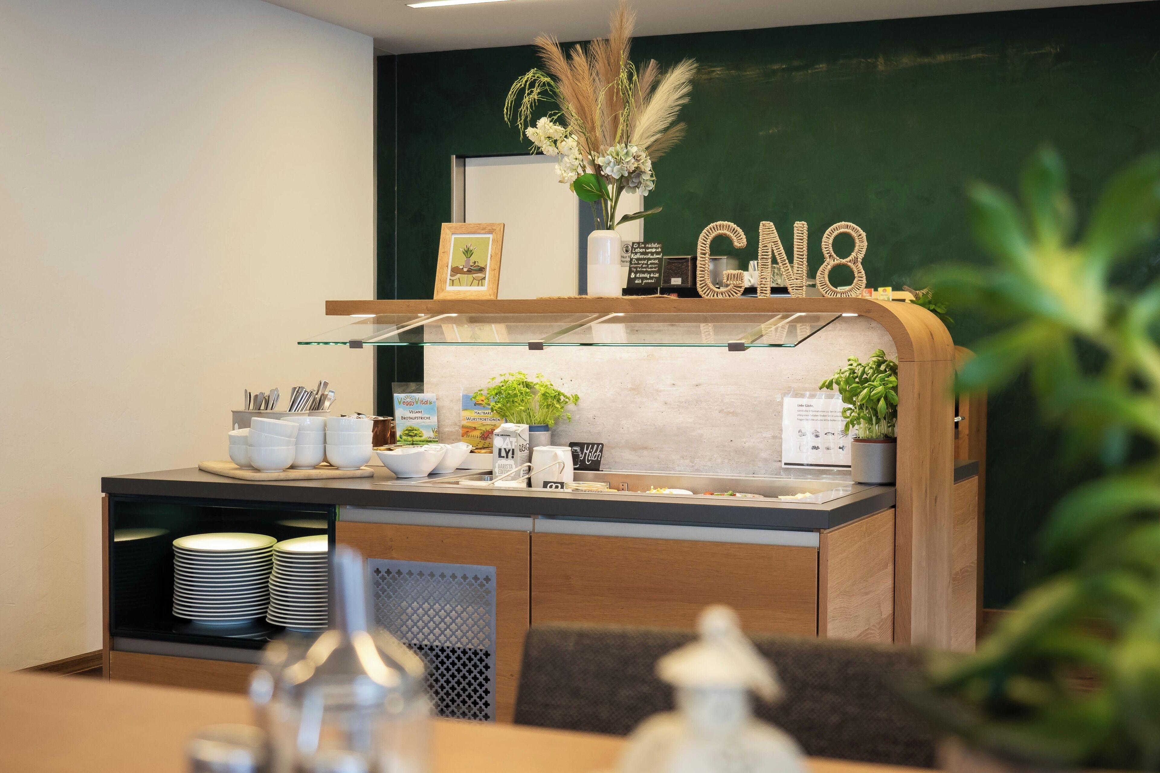Un área de bufé con un expositor de vidrio, una barra de madera y una pared verde con las letras "CN8".