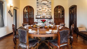 Comedor formal con una mesa redonda, sillas de madera y una pared decorativa de piedra.