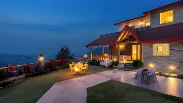 A two-story house with a covered patio area, outdoor seating, and a view of the mountains. - amã Stays & Trails Kedar Villa, Mukteshwar (Mukteshwar)