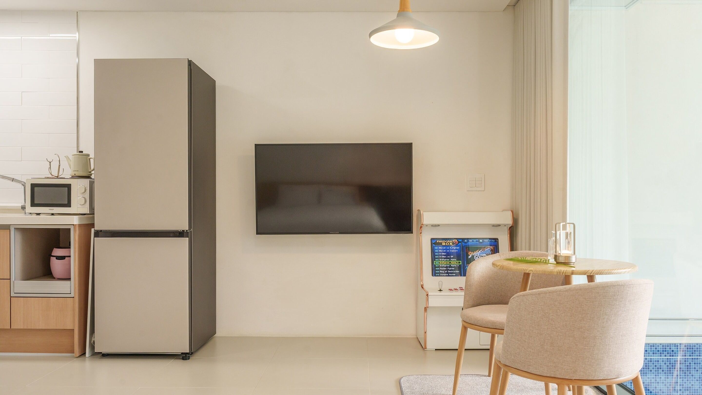 A modern kitchen with a built-in refrigerator, microwave, and a flat-screen TV mounted on the wall.
