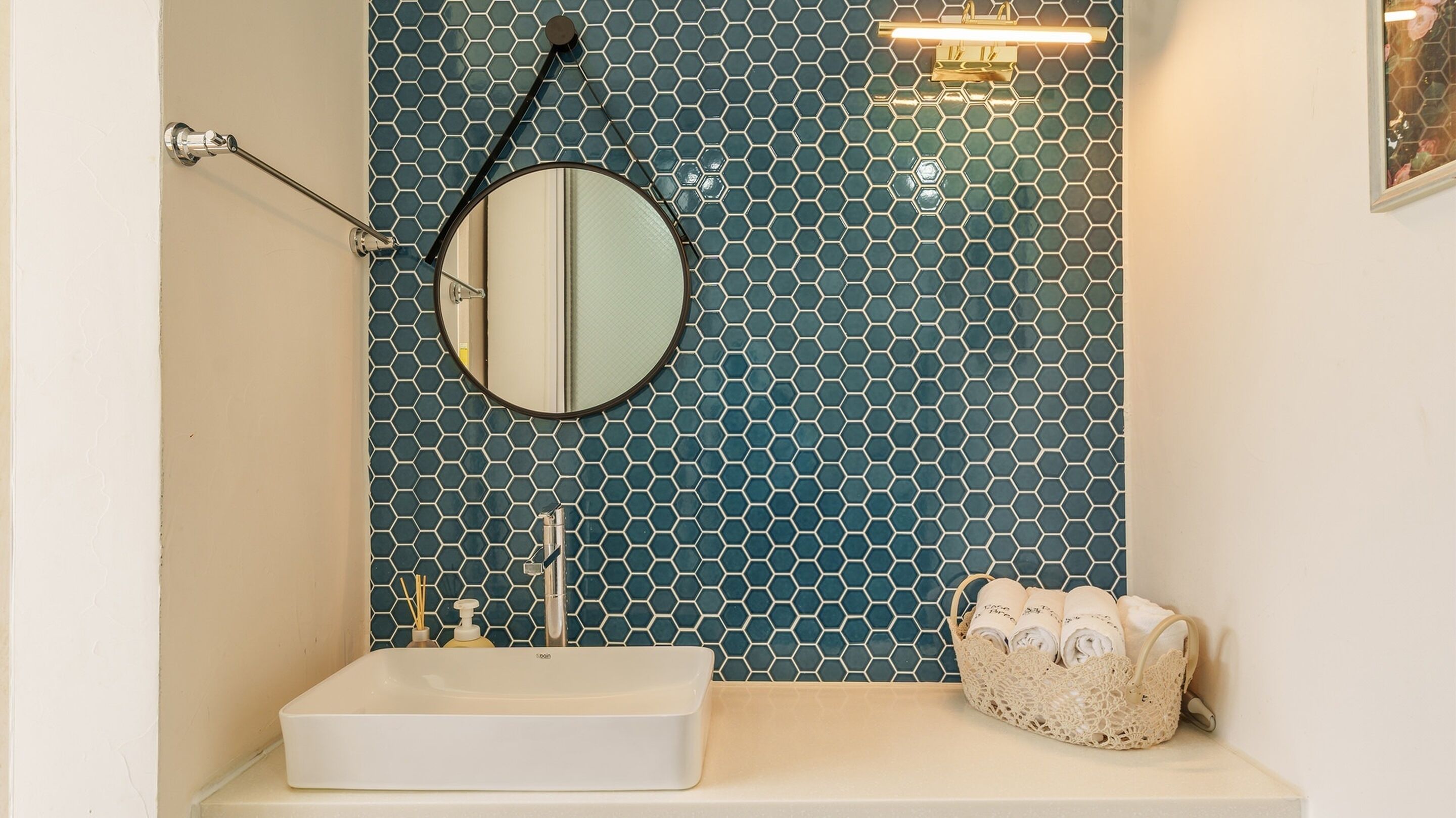 A bathroom with a white sink, a round mirror, and a towel rack.
