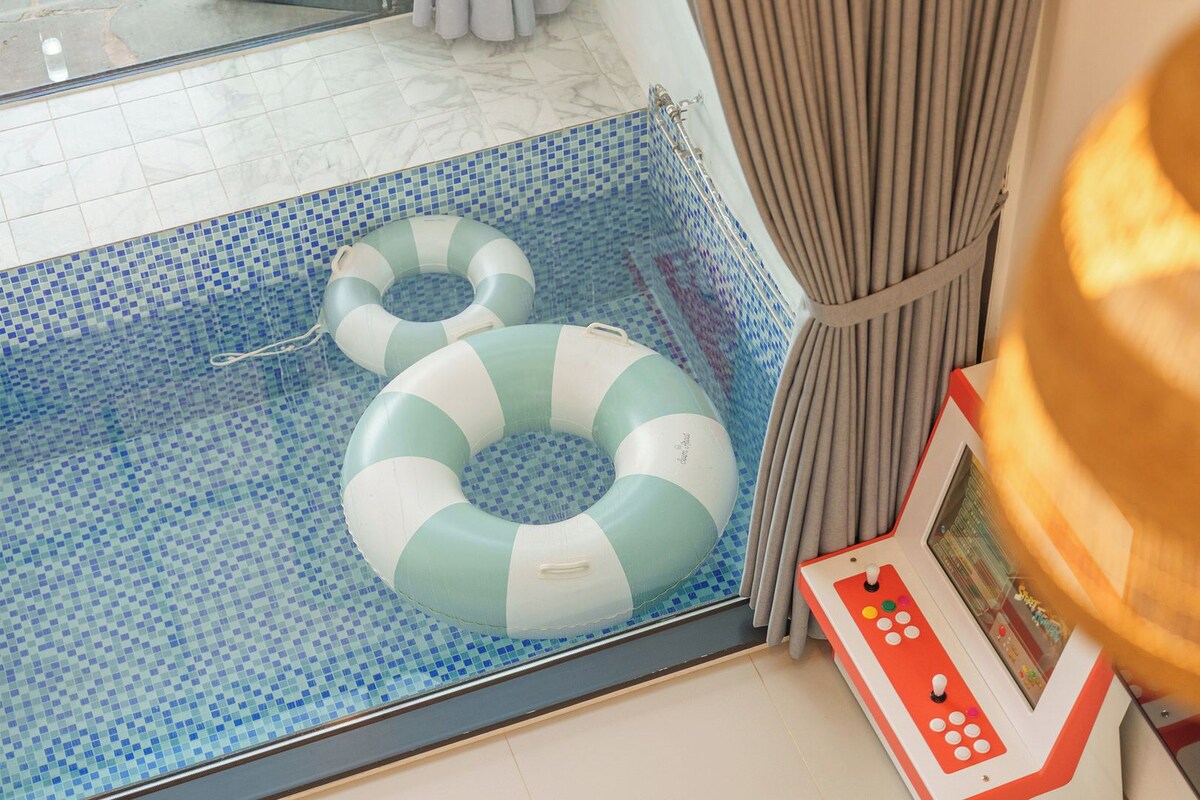 A swimming pool with two inflatable rings, a poolside control panel, and a curtain.