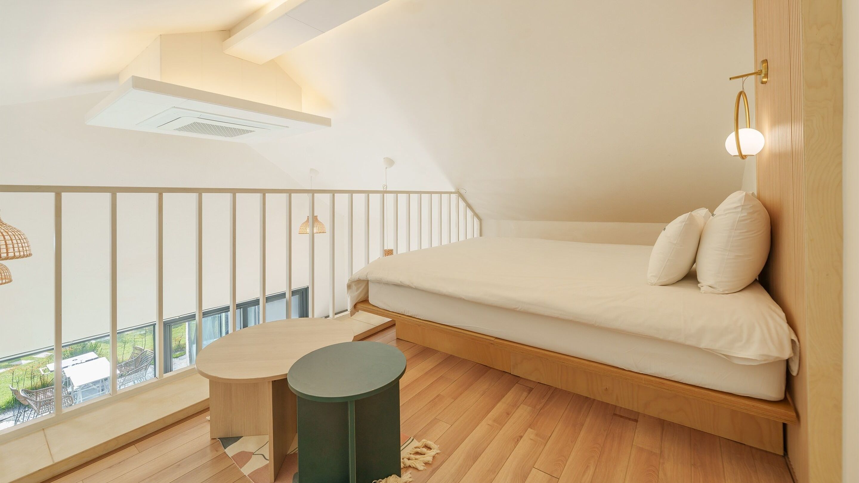 A modern loft bedroom with a built-in bed, a small round table, and a balcony with a view.