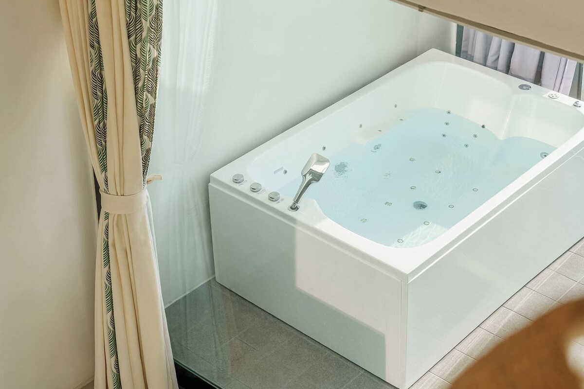 A modern bathroom with a freestanding bathtub, a shower area, and a glass door leading to a balcony.