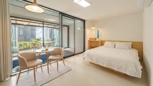 A modern hotel room with a large bed, a dining area with chairs, and a view of the city through large windows. - Gyeongju Rose Breeze Pool Villa Pension (Gyeongju)