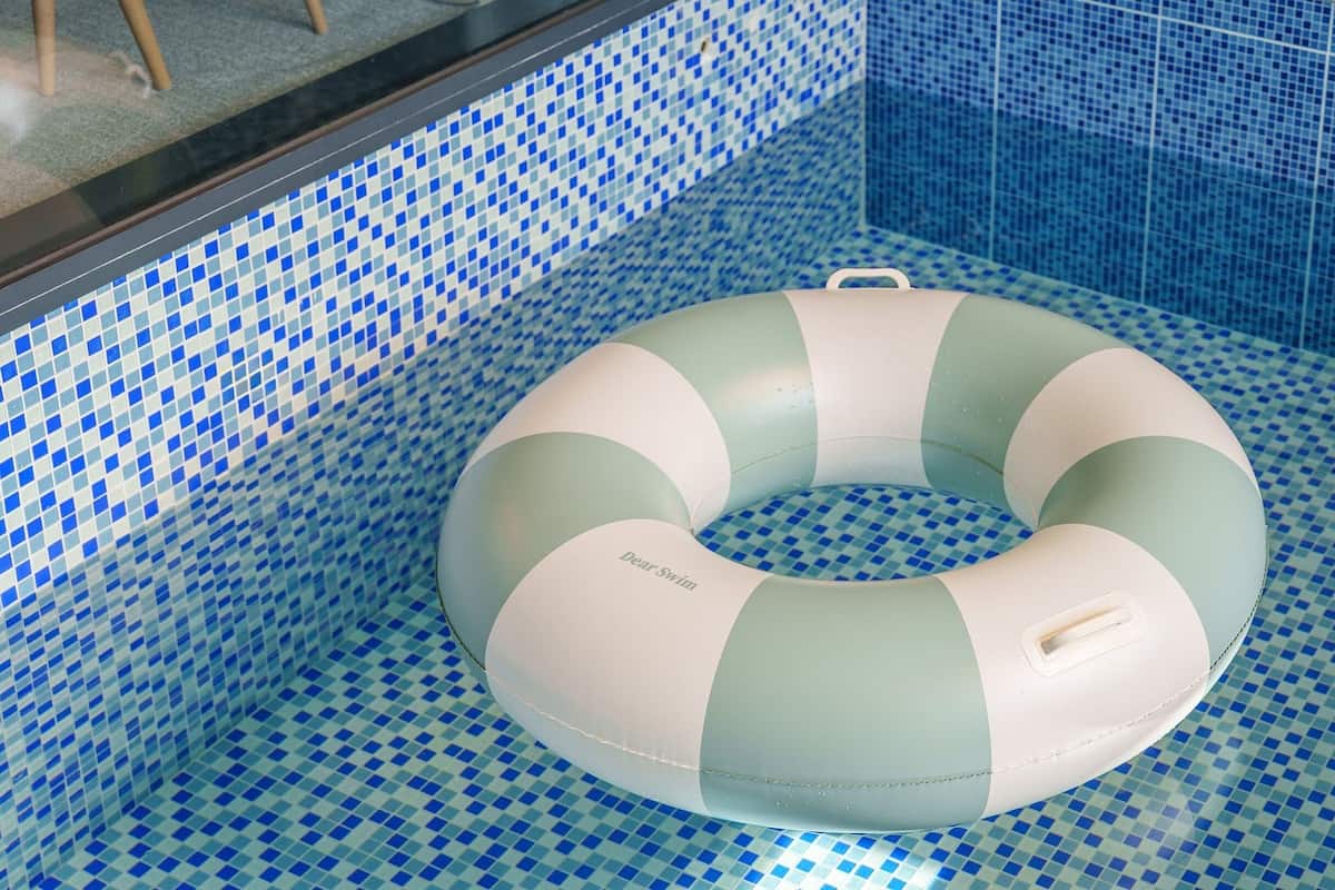 Ein Schwimmbecken mit Schachbrettmuster und einem weißen und grünen Schwimmreifen.