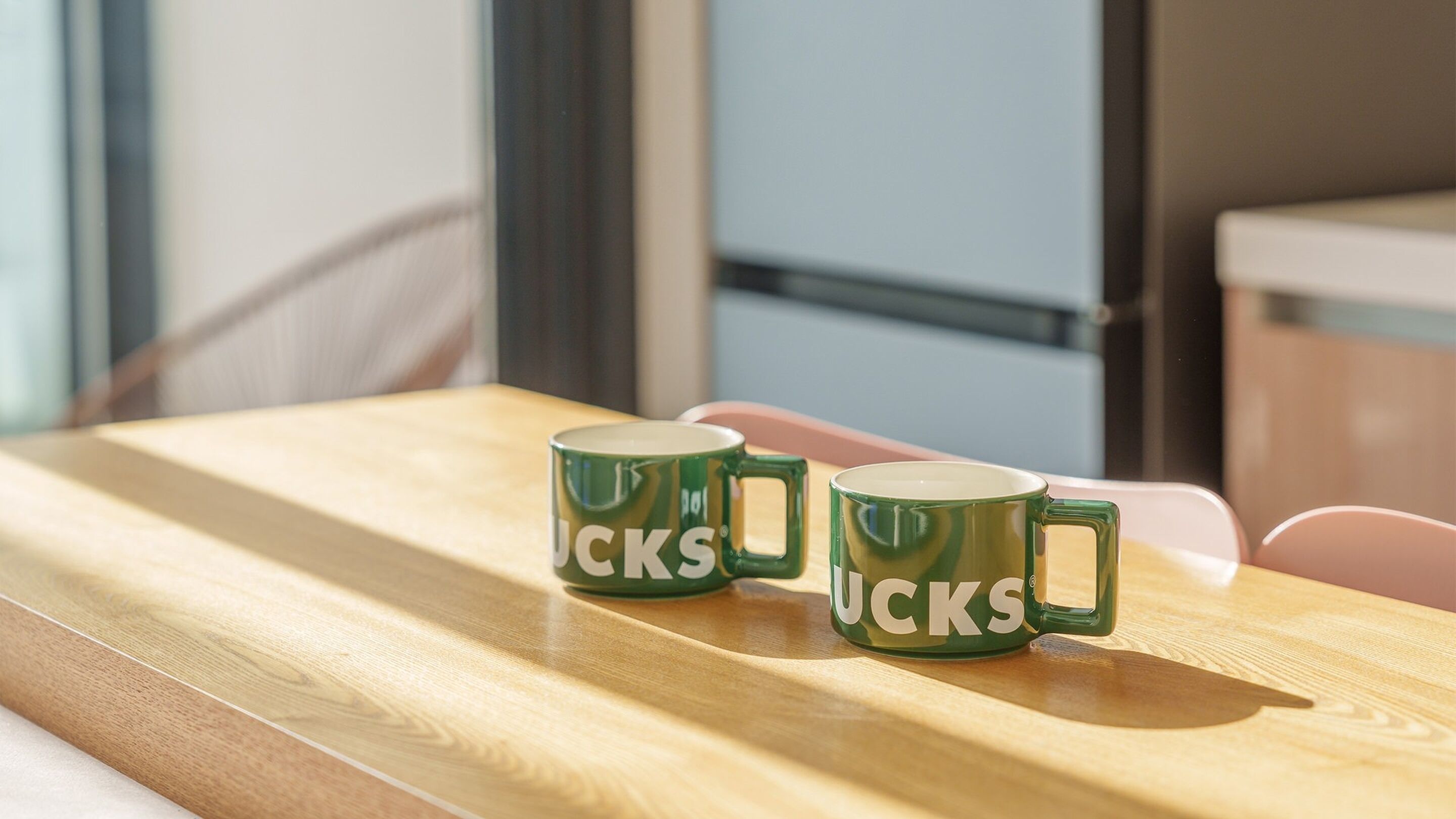 Una mesa de madera con tres tazas de café verdes que tienen la palabra "JACKS" escrita.