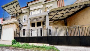 A two-story house with a balcony, a staircase, and a gated entrance. - Hotel O Sidomulyo Heritage (Mojokerto)