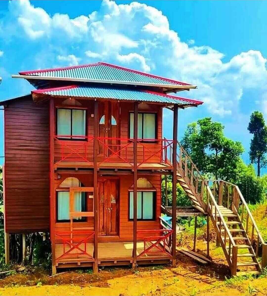Een houten chalet met twee verdiepingen, een balkon, een trap en uitzicht op het omliggende landschap.