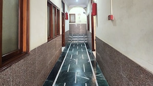 A hallway with a marble floor, wooden doors, and a fire extinguisher on the wall. - Hotel Step Inn Gold (New Delhi)