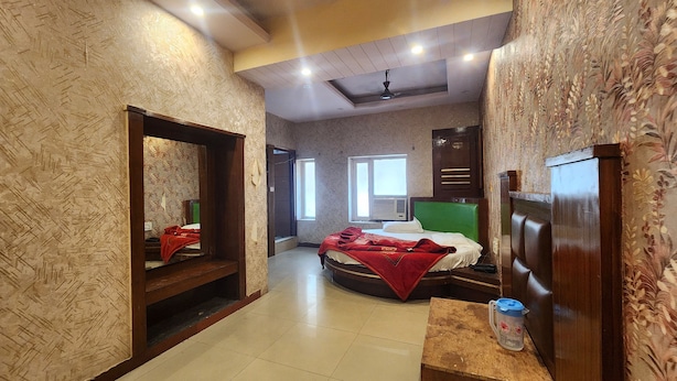 A hotel room with a bed, a wooden headboard, a mirror, a window, and a small table with a container. - Hotel Step Inn Gold (New Delhi)