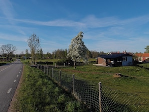 Un camino rural con una cerca, una casa pequeña y árboles.