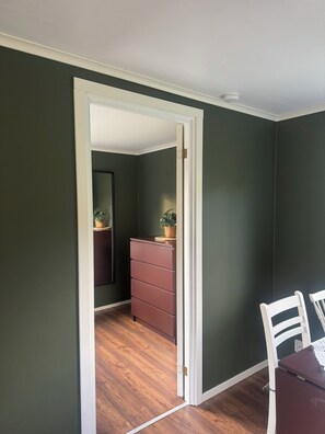 Una habitación con piso de madera, un aparador y una silla.