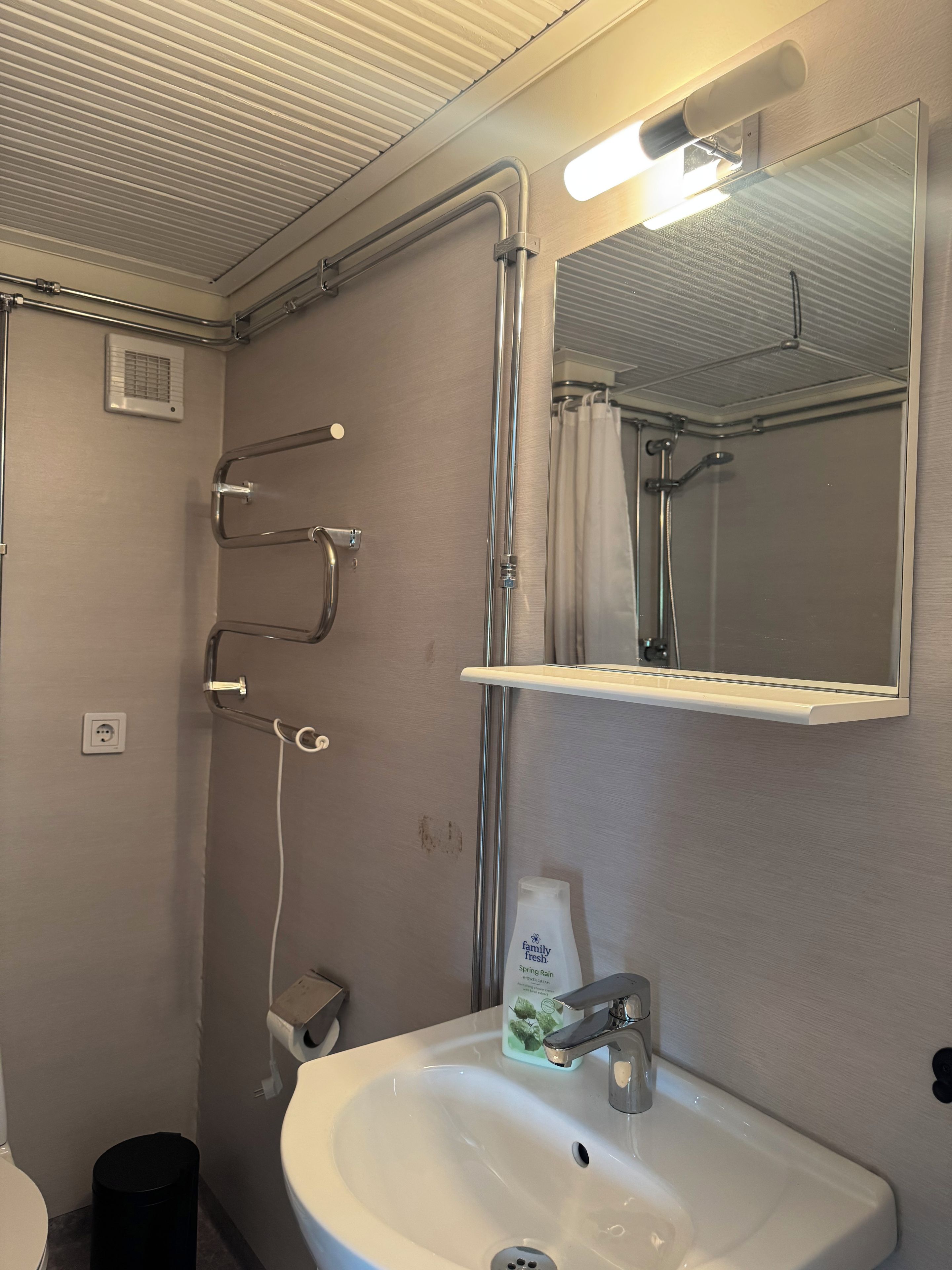 A bathroom with a white sink, a mirror, a shower with a glass door, and a towel rack.
