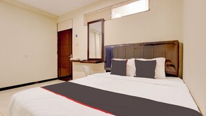Una habitación de hotel con una cama grande, un cabecero de madera, una mesita de noche con una lámpara y un espejo en la pared.