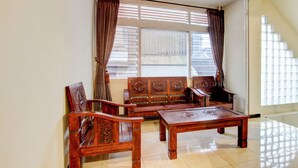Una habitación con sofá de madera, una mesa a juego y un ventanal con persianas.