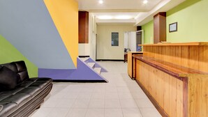 Un área de recepción con mostrador de madera, un sofá de cuero negro y una escalera que lleva a otra habitación.