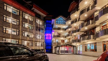 A hotel with multiple floors, balconies, and a brightly lit entrance.