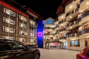 A hotel with multiple floors, balconies, and a brightly lit entrance. - HOTEL NAVEEN MANALI (Manali)