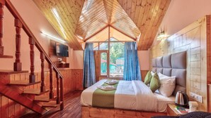 Un dormitorio de cabaña de madera con una cama, un televisor, una escalera de madera y vistas a través de una ventana.