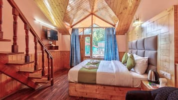 A wooden cabin bedroom with a bed, a TV, a wooden staircase, and a view through a window.