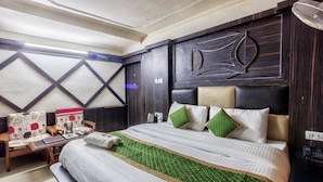 Une chambre d’hôtel avec un grand lit, une table de chevet, une chaise et un ventilateur fixé au mur.
