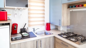 Een moderne keuken met een ingebouwd gasfornuis, een spoelbak en een raam met zonwering.
