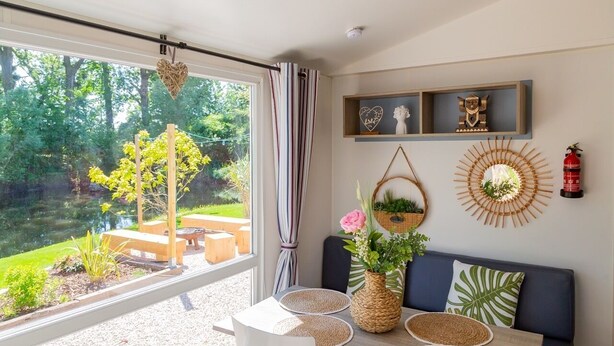 Een moderne woonkamer met een groot raam, een eethoek en een wand versierd met planken en decoratie.